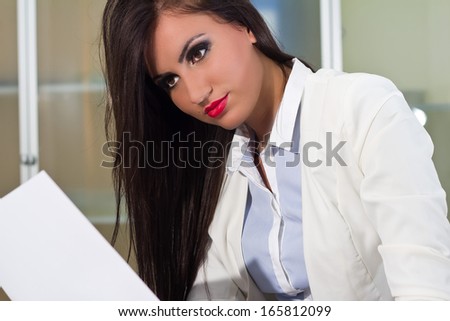 Beautiful woman sitting behind the desk and reading files in the office