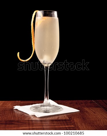 champagne cocktail served on a bar top isolated on black garnished with an orange twist