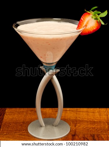 strawberry shake in a martini glass garnished with a fresh sliced strawberry isolated on black
