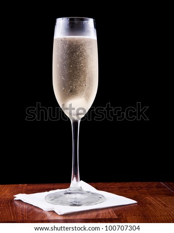champagne flute served with sparkling wine and a sugar cube isolated on a black background