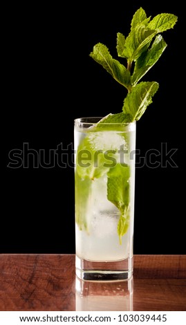 fresh mojito on a bar top isolated on a black background garnished with fresh organic mint
