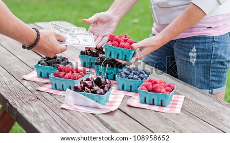 Fresh berries for sale with money transfer of money and berries between two people