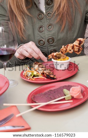 grilled chicken skewers served on a red plate with a mango salsa