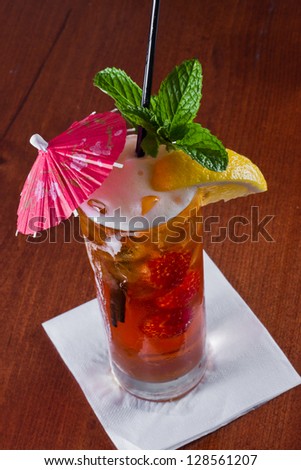 closeup of a long island red tea served on a dark bar top garnish with a lemon