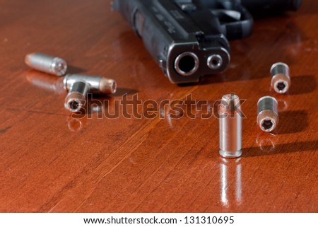 closeup of a hallow point bullet with a gun on a table