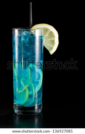 bright blue lemonade served in a tall glass isolated on a black background