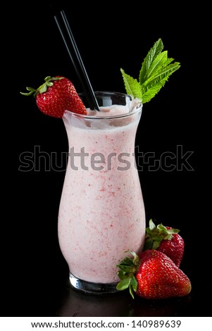 strawberry milk shake isolated on a black background garnished with fresh green mint