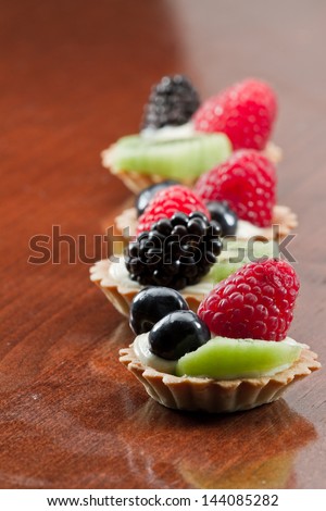 bite size fruit tarts with fresh fruit served in a row