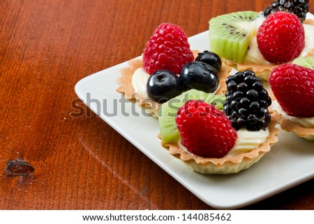 bite size fruit tarts with fresh fruit served on a white plate