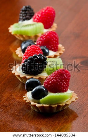 bite size fruit tarts with fresh fruit served in a row