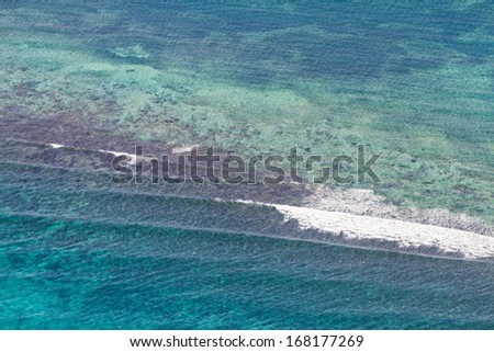 aerial view of the barrier reef of the coast of San Pedro, Belize. with large waves breaking away from the coast
