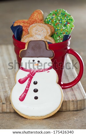 close up of holiday Christmas cookie in the shape of a snow man with a red coffee cup filled with cookies