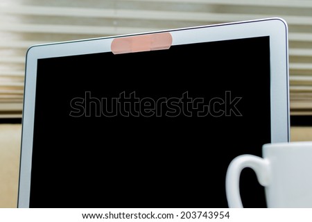 close up of a band aid on a web cam on a laptop in a home setting