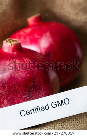 food labeling concept with bright red pomegranates and a GMO label