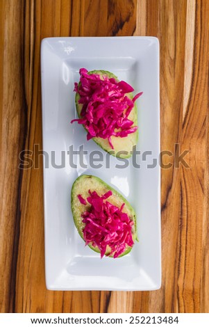 serving of fermented or cultured purple cabbage paired with an avocado on a white plate