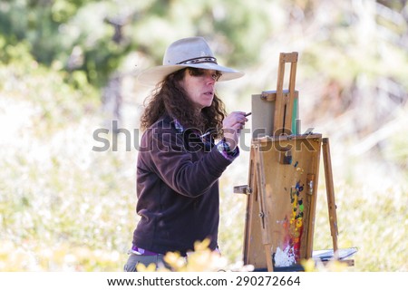 Lake Tahoe, Nevada - April 29 : Woman artist painting on canvas a beautiful landscape, April 29 2015 Lake Tahoe, Nevada.