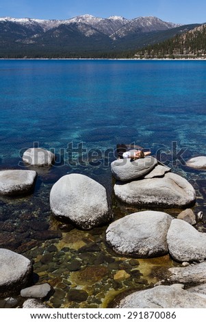 beautiful woman on a boulder relaxing and enjoying a beautiful day at the lake