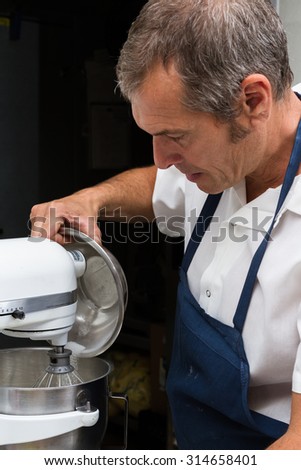 professional chef pouring ingredients into a mixer preparing for dinner service