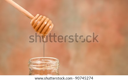 honey dripping from a wooden dipper into a jar