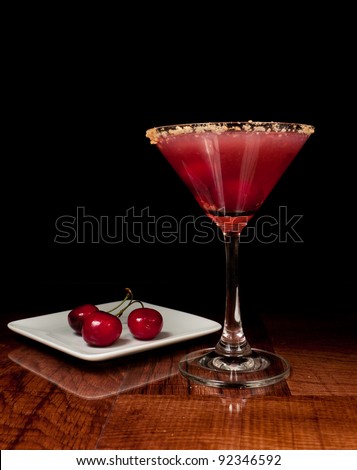 sour cherry martini on a bar top garnished with two cherries sharing one stem