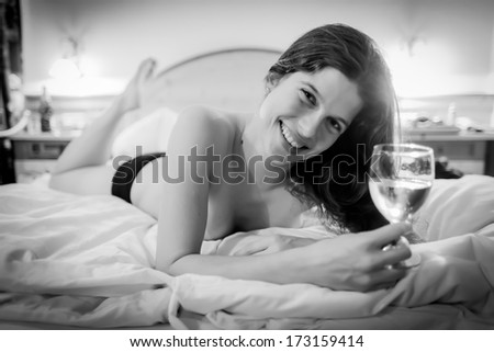 Romantic evening - Young woman in a bed drinking champagne