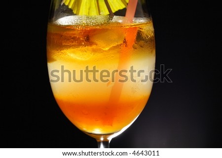 Detail of triple layered drink with spiral lemon slice, umbrella and straw in studio light