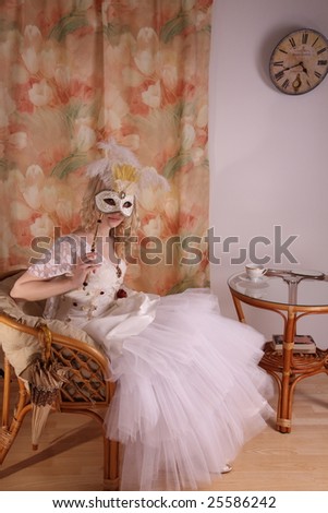Beautiful model wearing a wedding dress and Venetian mask, studio