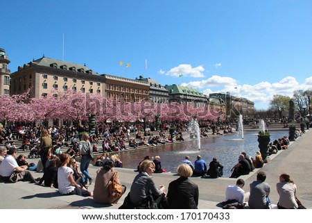 STOCKHOLM, SWEDEN - May 7: People relaxing in the sun by a pond and blossoming cherry trees in central Stockholm, shown on May 7, 2013 in Stockholm.