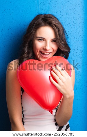 Love and valentines day woman holding heart smiling cute and adorable on blue background. Beautiful caucasian woman in love.