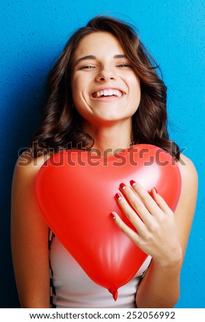 Love and valentines day woman holding heart smiling cute and adorable on blue background. Beautiful caucasian woman in love.