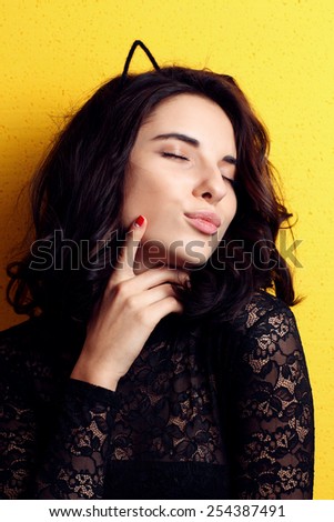 Sexy  woman with  cat\'s eyes and a fashionable hairstyle poses in studio on yellow background.