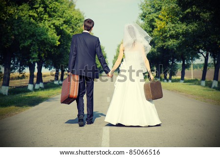 couple holding suitcases  on countryside road