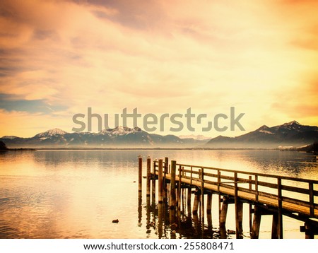 wooden jetty on lake chiemsee with alps in background