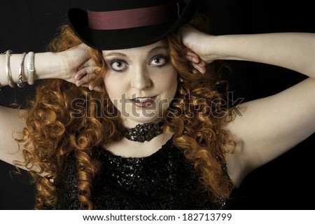Beautiful young woman with long, curly red hair wearing vintage tank top and top hat
