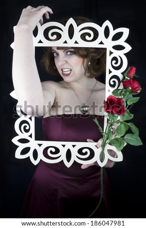 Beautiful woman holding white wooden frame with red roses with her arms wrapped around frame