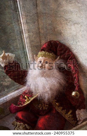 Christmas elf figure sitting in window with long white beard