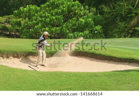 PATTAYA, THAILAND - MAY 29: Unidentified asian man in sandtrap on 8th hole on Green Valley St Andrews golf course on May 29, 2013. Pattaya has 25 golf courses close to the city.