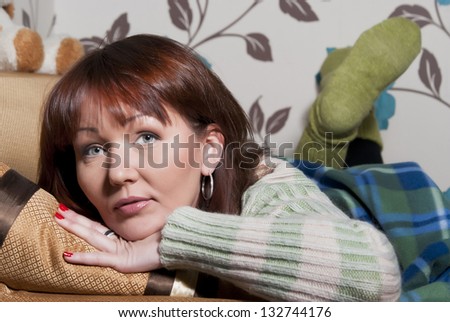 Beautiful woman lying on the couch wrapped in a blanket