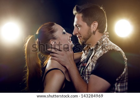 Couple of lovers. Couple of independent steep young people hugging, looking into each other\'s eyes and laughing, on a black background with two luminous lanterns