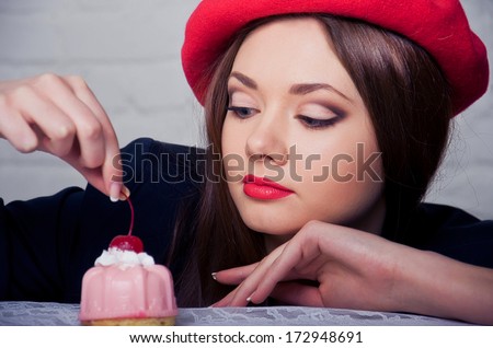 Beautiful young French Woman with pink Cake on top of which cherry