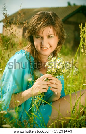 beautiful girl sitting in a field with a bouquet of flowers