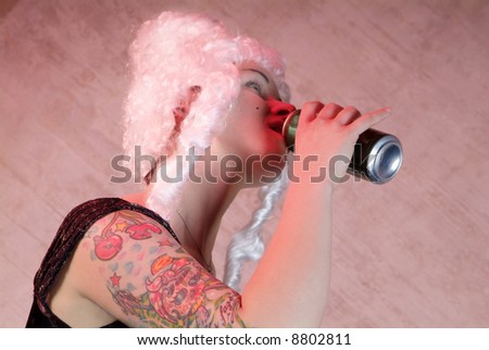woman with white peruke and tattooed upper arm drinks from the can