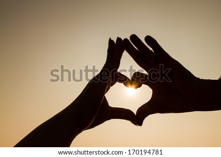 heart shape from 2 people hands with sun inside