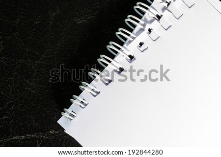 part of white spiral notebook on black leather skin