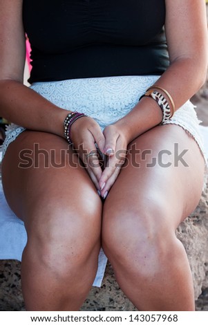 woman is sitting and holds her hands on her knee