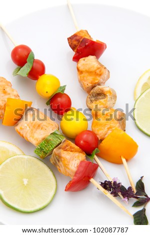 Closeup of grilled salmon and vegetable skewers with fresh tarragon and green salad