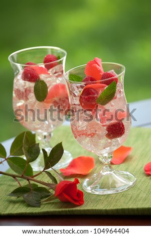Closeup of two glass of white raspberry rose drink on outside table.