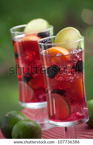 Closeup of two glass of Red Sangria - apricot, lime and blackberry - on outside table.