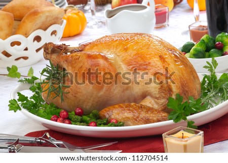 Garnished roasted turkey on fall festival decorated table with horn of plenty and red wine