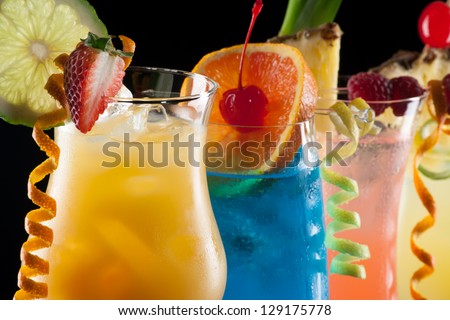 Tequila Sunrise, Blue Lagoon, Rum Runner, and Bahama Mama cocktails over black background on reflection surface